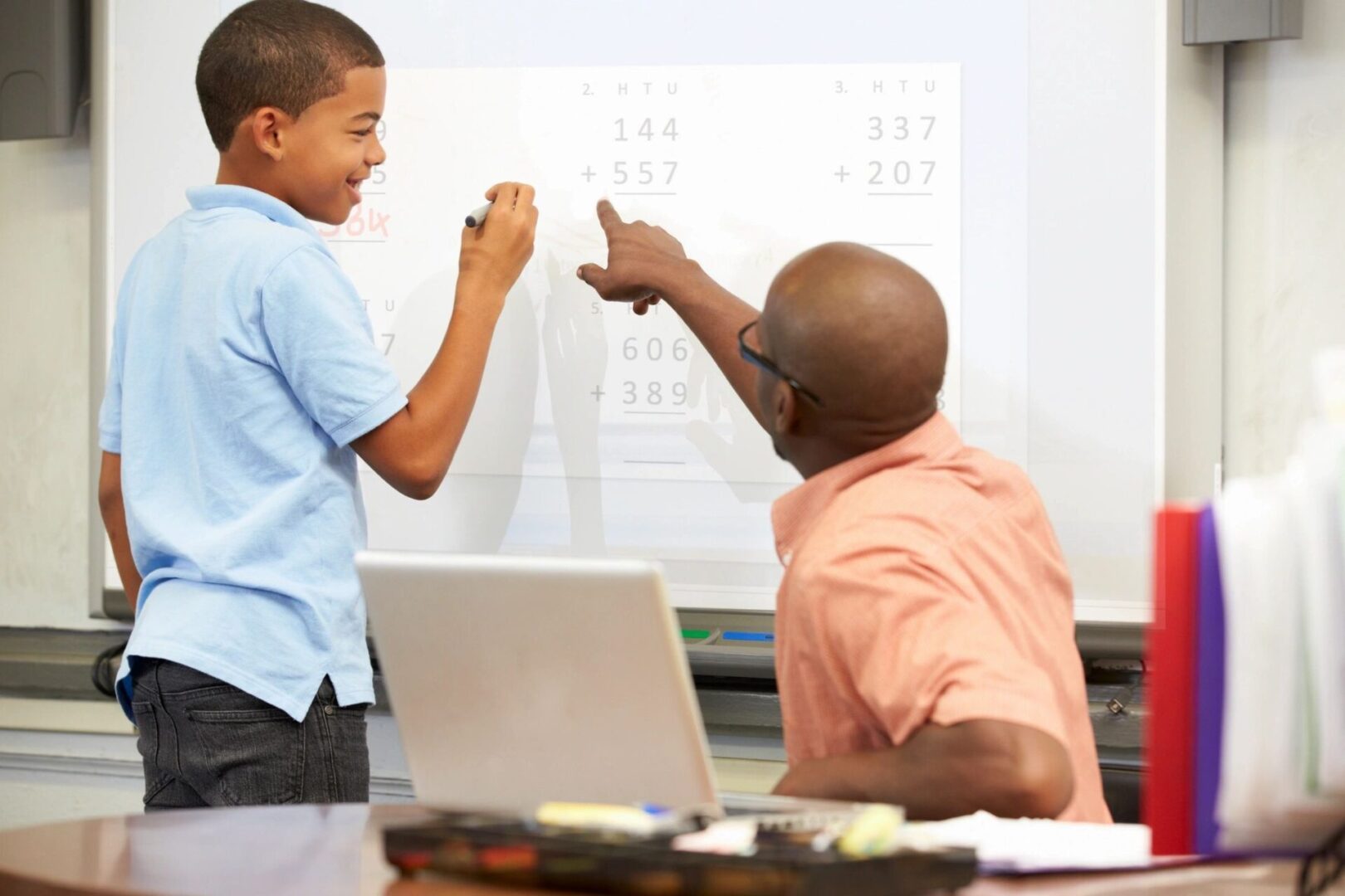 A teacher teaching a student inside a class is shown